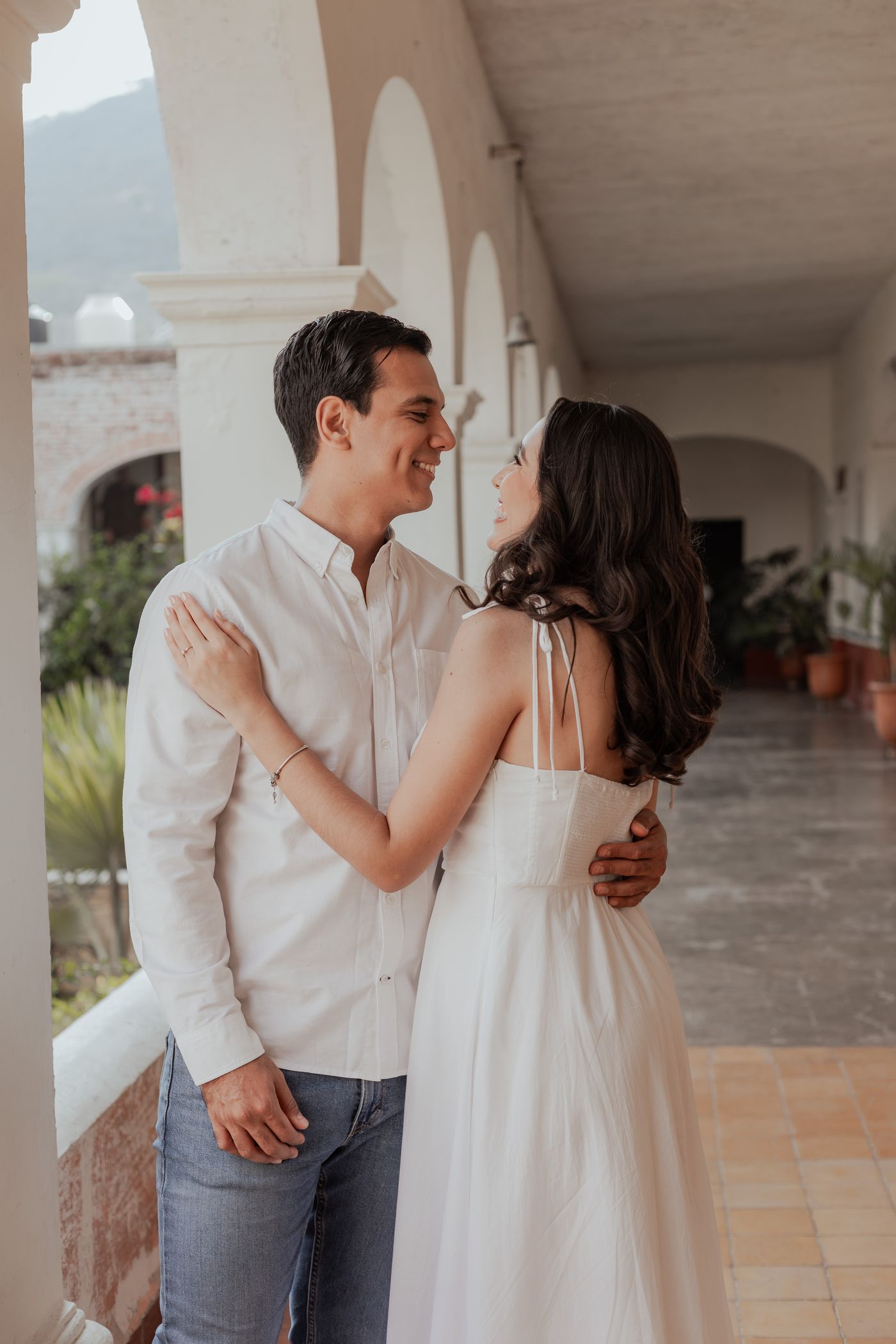 Alma y Pedro sonriendo bajo los arcos de la hacienda