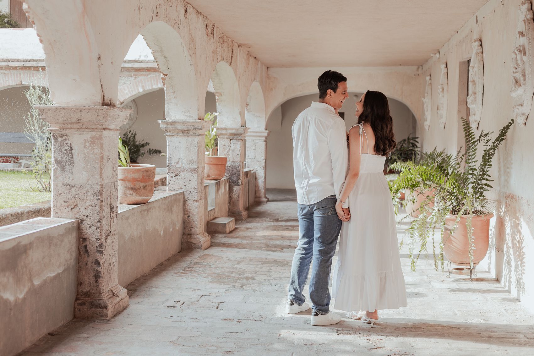 Alma y Pedro caminando de la mano por el corredor de arcos